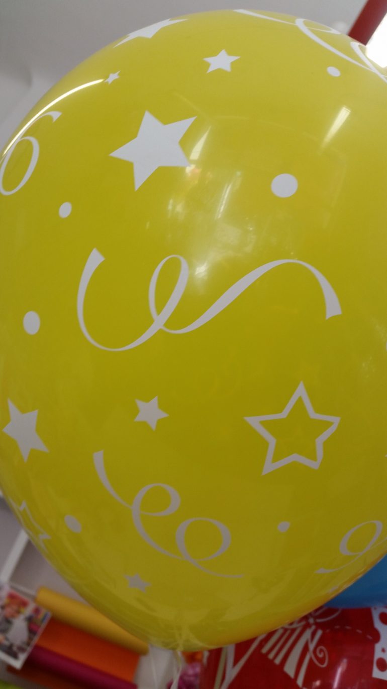 gelber Latexballon mit Sternen und Luftschlangen